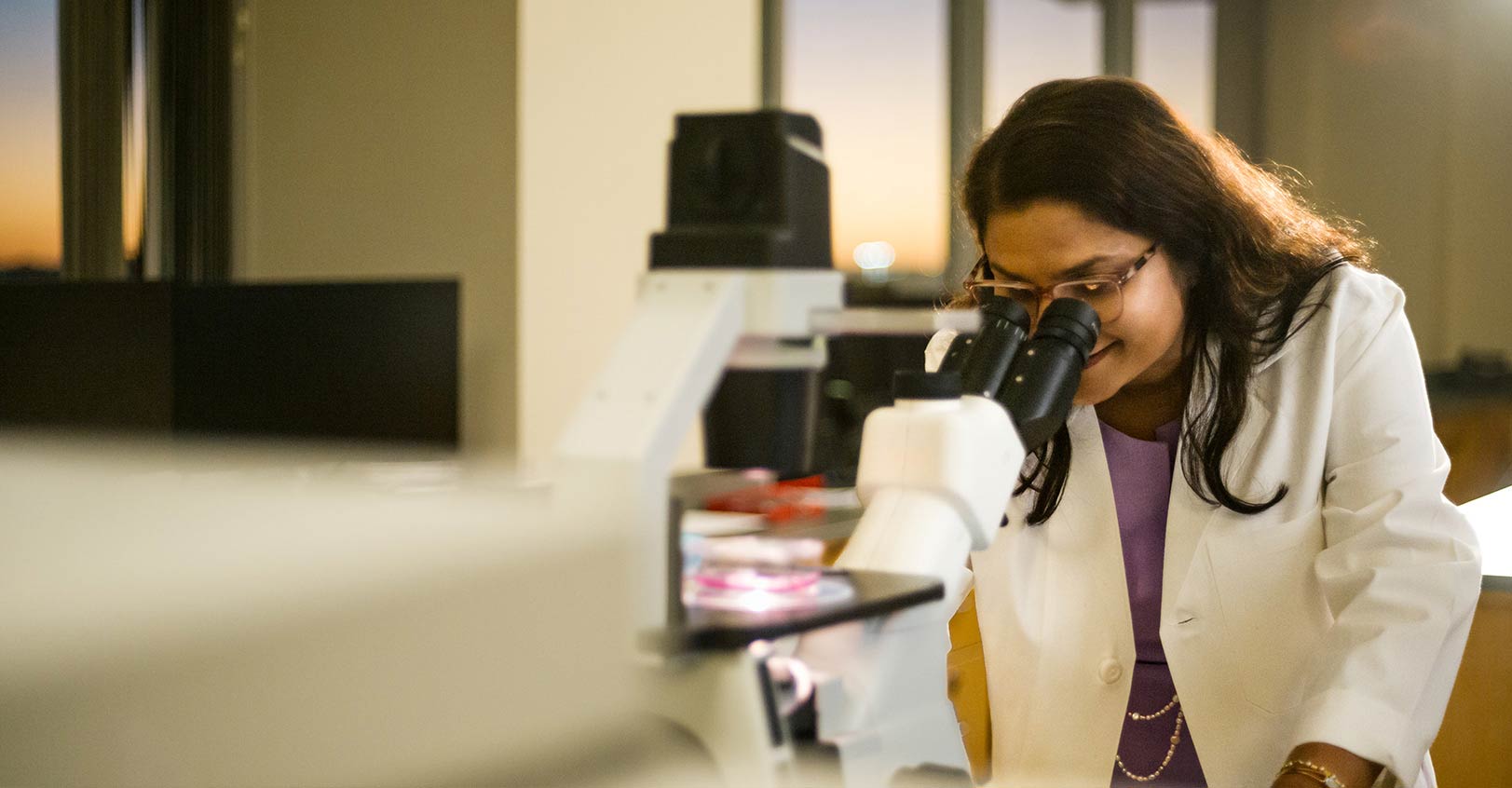 A clinical researcher using microscope in a clinical setting